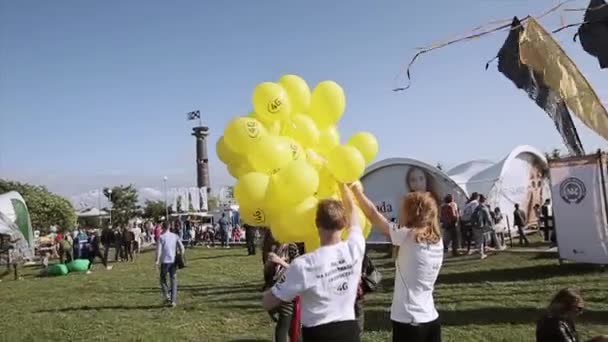 Sankt Petersburg, Rosja-16 lipca, 2015: ludzie na letni festiwal w zielonym parku. Dziewczyna i chłopiec z wielu żółtych balonów powietrza. Rozrywka. — Wideo stockowe
