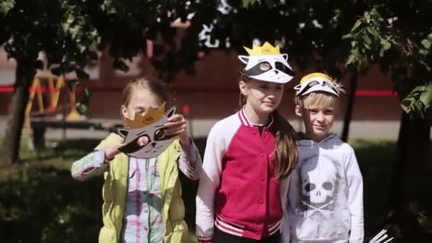 俄罗斯圣彼得堡 - 2015年7月16日：戴着滑稽面具的孩子们在镜头前摆姿势，面带微笑。夏季节日。晴天。童年。假期 — 图库视频影像