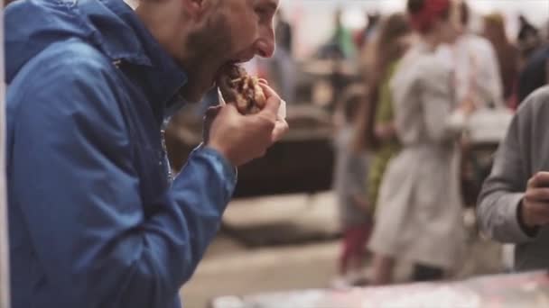 Sankt Petersburg, Rosja-16 lipca 2015: dwóch mężczyzn jedzenia Hamburger na letni festiwal. Wietrzny dzień. Ulica Fast food. Rozrywka. Ludzi — Wideo stockowe