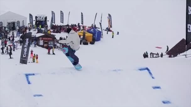 Sochi, Rusko-29. březen 2016: snowboardista v helmici, skok z odrazové desky. Zasněžené hory. Lyžařské středisko. Davy lidí. — Stock video