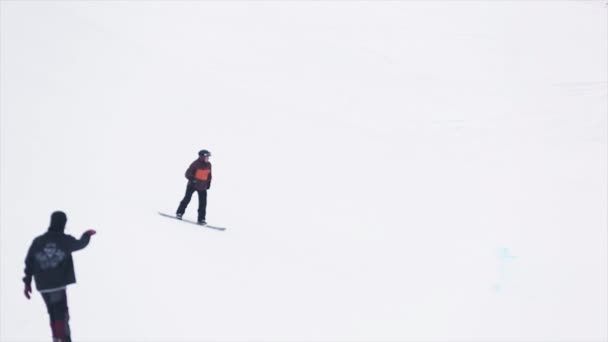 SOCHI, RUSIA - 29 DE MARZO DE 2016: Snowboarder en salto de casco desde trampolín. Montañas nevadas. Banderas. Concurso. Deporte extremo. Esquiadores — Vídeos de Stock