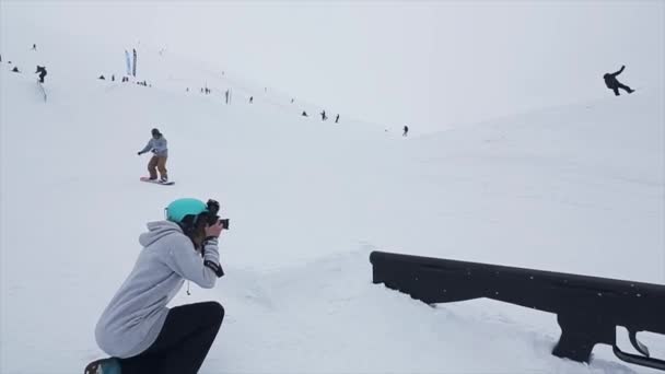 SOCHI, RUSIA - 29 DE MARZO DE 2016: El hombre de la cámara dispara deslizamiento snowboarder en el sendero en la pendiente, fallando. Estación de esquí en las montañas. Desafío . — Vídeo de stock