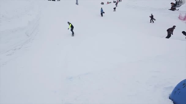 Sochi, Rusko-29. březen 2016: snowboardista na odrazové desce na svahu. Lyžařské středisko v horách. Výzva. Přilba. Lyžařské vleky — Stock video