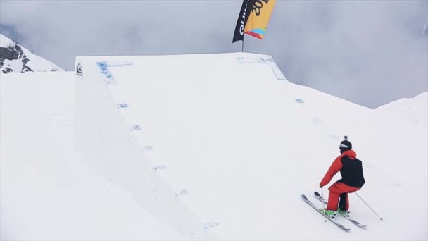 SOCHI, RUSIA - 29 DE MARZO DE 2016: Esquiador en uniforme de salto desde trampolín, hacer acrobacias extremas. Montañas nevadas. Concurso. Paisaje — Vídeos de Stock