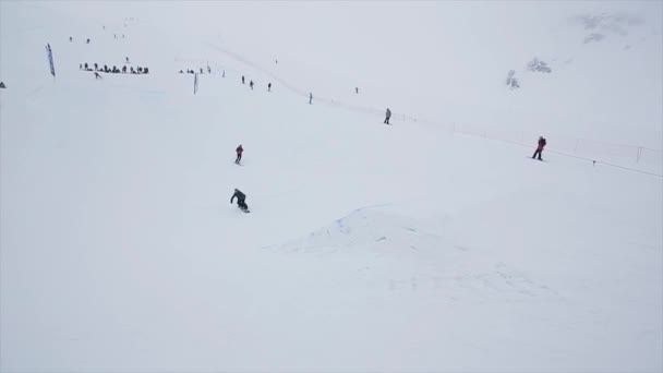 SOCHI, RUSIA - 29 DE MARZO DE 2016: Salto snowboarder sobre trampolín en pendiente. Estación de esquí en montañas nevadas. Desafío. Gente. Stunt. — Vídeos de Stock