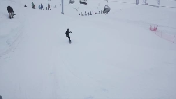 SOCHI, RUSIA - 29 DE MARZO DE 2016: Salto snowboarder desde trampolín en pendiente, hacer voltear. Estación de esquí en montañas nevadas. Desafío . — Vídeos de Stock