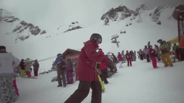 SOCHI, RUSIA - 31 DE MARZO DE 2016: Los snowboarders saltan sin un zapato en la ladera en el sendero nevado. Sonríe en cámara. Gente. Competencia — Vídeo de stock