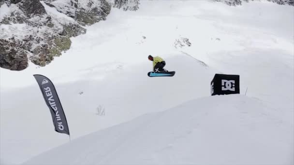 SOCHI, RÚSSIA - Março 31, 2016: Snowboarder fazer acrobacias extremas, saltar do trampolim. Paisagem de montanhas nevadas. Concurso . — Vídeo de Stock