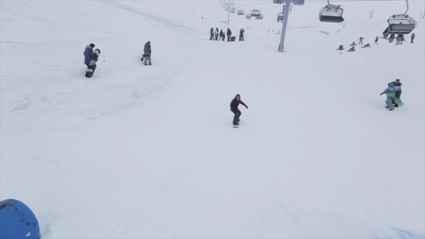 SOCHI, RUSIA - 29 DE MARZO DE 2016: Snowboarder girl jump on springboard at slope. Estación de esquí en montañas nevadas. Desafío. Nieve cae — Vídeo de stock