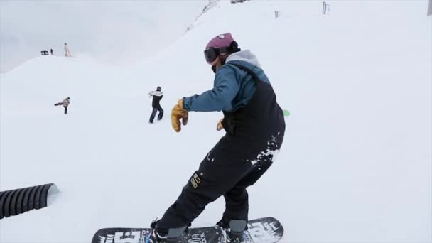 SOCHI, RUSIA - 31 DE MARZO DE 2016: Paseo de snowboarder sobre trampolín largo negro, salto. Paisaje. Montañas nevadas. Concurso. Gente . — Vídeos de Stock