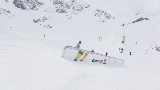 SOCHI, RUSIA - 31 DE MARZO DE 2016: Snowboarder hace un tobogán en el sendero de hierro en la pendiente. Paisaje. Montañas nevadas. Competencia. Concurso — Vídeos de Stock