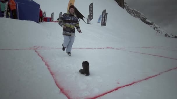 SOCHI, RUSSIA - 31 MARZO 2016: Snowboarder senza una scarpa salta per secondo sul pendio in montagna innevata. Sorridi. Gente. Sfida — Video Stock