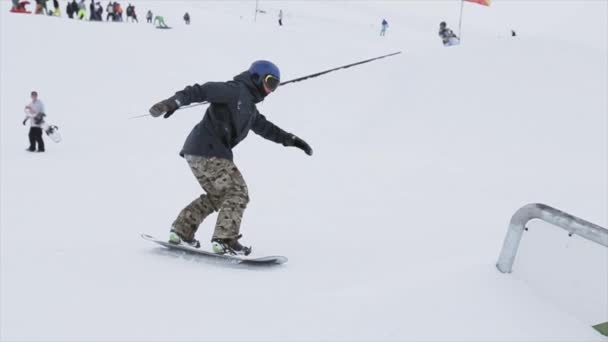 Sochi, Rusko - 31 března, 2016: Snowboardista, aby překlopit přes železnou stezkou na svahu. Extrémní sport. Zasněžené hory. Konkurence. Soutěž — Stock video