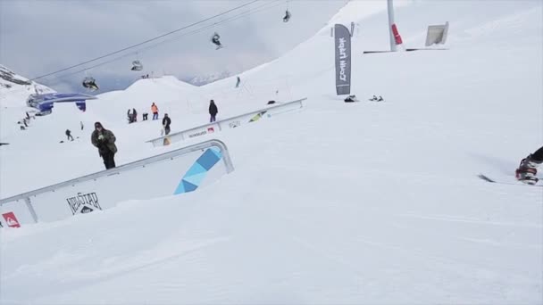 Sochi, Rusland - 31 maart 2016: Schuif Snowboarder zorg terug op ijzer trail op helling. Landschap. Besneeuwde bergen. Competitie. Wedstrijd — Stockvideo