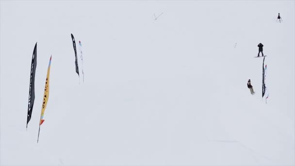 SOCHI, RUSIA - 31 DE MARZO DE 2016: Snowboarder hacer voltereta extrema, saltar desde el trampolín. Montañas nevadas. Concurso. ondeando banderas — Vídeos de Stock