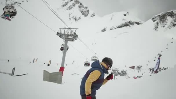 Sochi, Rusko - 31 března, 2016: Snowboardista jízdu na svahu v zasněžené horské. Přesvědčte se, extrémní skok z trampolíny. Šedý mrak nebe — Stock video