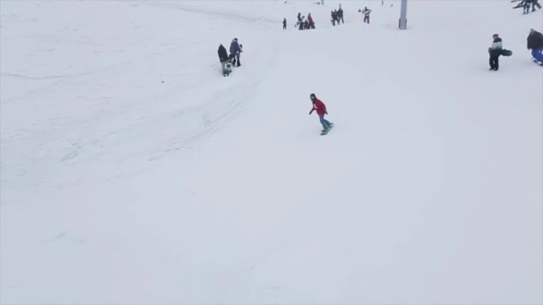 ソチ, ロシア - 2016 年 3 月 29 日: スノーボーダーは斜面を踏み台にジャンプ、空気でボードをつかみます。雪に覆われた山々。チャレンジ。雪が降る — ストック動画