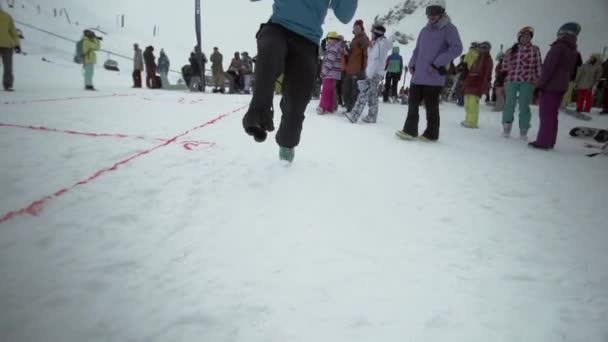 Sochi, Rusland - 31 maart 2016: Snowboarders springen zonder één schoen op helling besneeuwde pad. Lachen in de camera. Mensen. Uitdaging — Stockvideo