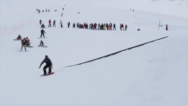 Σότσι, Ρωσία - 31 Μαρτίου 2016: Snowboarder βόλτα στην αφετηρία, κάνουν πίσω διαφάνεια στο μονοπάτι του σιδήρου. Τοπίο. Χιονισμένα βουνά. Διαγωνισμός — Αρχείο Βίντεο