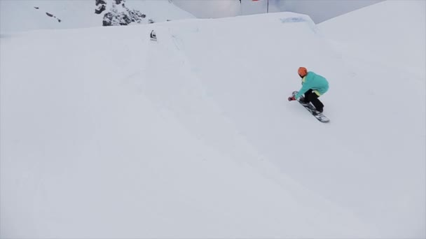 SOCHI, RUSIA - 31 DE MARZO DE 2016: Snowboarder hace un salto de altura extremo desde un trampolín en la montaña de nieve. Agarra el tablero en el aire. Concurso . — Vídeos de Stock