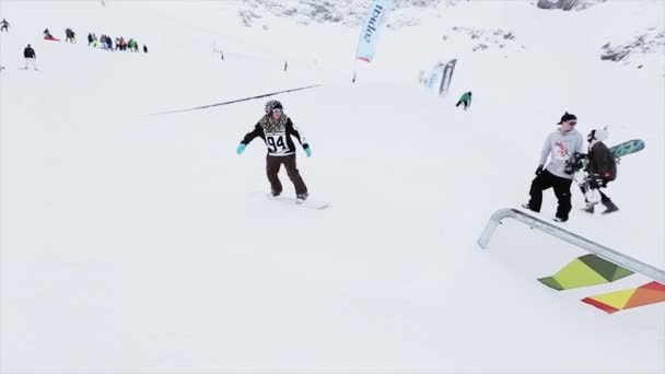 SOCHI, RUSIA - 31 DE MARZO DE 2016: Deslizamiento de snowboarder sobre pista de hierro en pendiente. Camarógrafo. Paisaje de montañas nevadas. Competencia — Vídeos de Stock