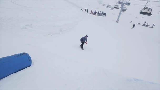 SOCHI, RUSIA - 29 DE MARZO DE 2016: Paseo de snowboard en trampolín en pendiente, voltear. Estación de esquí en montañas nevadas. Desafío. Público — Vídeos de Stock