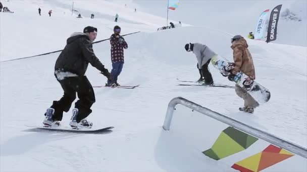 Sochi, Rusko-31. březen 2016: snowboardista se na svahu vyklouže po železné stopě. Krajina. Zasněžené hory. Soutěž. Lidé — Stock video