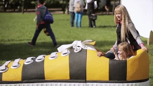 SAINT PETERSBURG, RUSSIA - 16 LUGLIO 2015: Due giovani ragazze prendono bootlace di enorme scarpa sportiva nera e gialla. In posa per una foto. Festival estivo — Video Stock