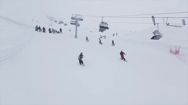 SOCHI, RUSIA - 29 DE MARZO DE 2016: Salto de esquiador sobre trampolín en pendiente. Estación de esquí en montañas nevadas. Desafío. Nieve cae. Gente — Vídeos de Stock