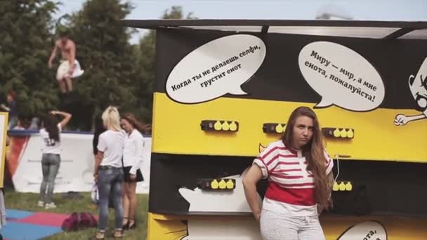 Sint-Petersburg, Rusland-16 juli 2015: verdrietig meisje op stand met telefoon opladen. Man hoogspringen op sport trampoline op zomer Festival. Zonnige — Stockvideo