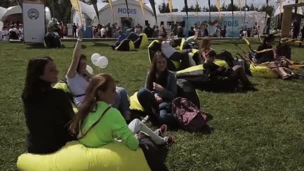 SAINT PETERSBURG, RUSSIA - JULY 16, 2015: People relaxing on beaanbags on summer festival. Black and yellow waving tapes. Sunny. Entertainment — Stock Video