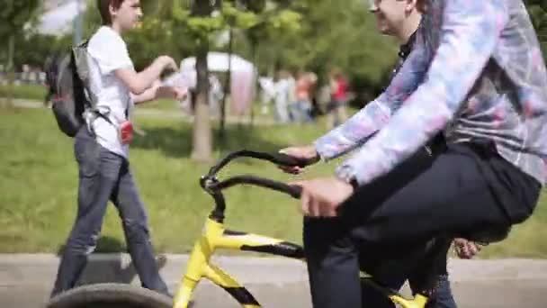 SAINT PETERSBURG, RÚSSIA - 16 de julho de 2015: Homem de óculos escuros passeia de bicicleta preta e amarela no festival de verão. Entretenimento. Dia ensolarado — Vídeo de Stock