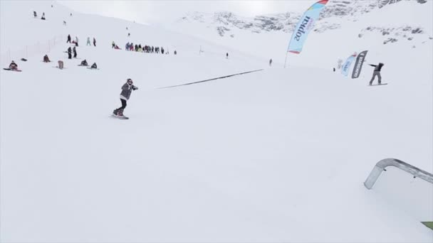 SOCHI, RUSSIA - 31 MARZO 2016: Scivolo snowboarder su pista in ferro sul pendio girare. Cameraman. Montagne innevate. Competizione. Persone — Video Stock