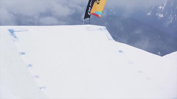 SOCHI, RÚSSIA - MARÇO 29, 2016: Snowboarder em salto uniforme de trampolim, fazer virar no ar, pegar bordo. Montanhas nevadas. Extremo — Vídeo de Stock