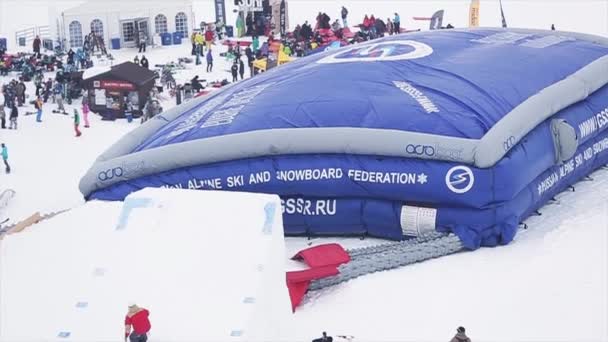 SOCHI, RUSIA - 29 DE MARZO DE 2016: Salto snowboarder desde trampolín, voltear en el aire, caer en un trampolín enorme. Montañas. Entrenamiento. Gente — Vídeo de stock