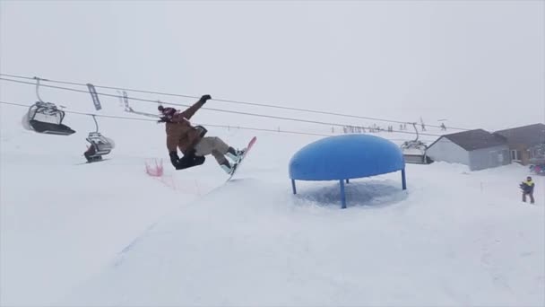Sotschi, Russland - 29. März 2016: Snowboarder springen am Hang mit der Hand auf das Sprungbrett. Skigebiet in schneebedeckten Bergen. Herausforderung. — Stockvideo