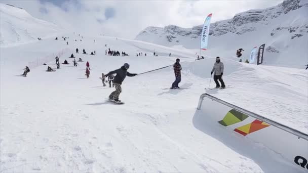 Σότσι, Ρωσία - 31 Μαρτίου 2016: Snowboarder κάνει ακραία flips, τσουλήθρα σιδερένια μονοπάτι σε πλαγιά. Τοπίο. Χιονισμένο βουνό. Ανταγωνισμού — Αρχείο Βίντεο