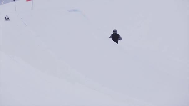 SOCHI, RÚSSIA - Março 31, 2016: Snowboarder jump from springboard slide on slope in snowy mountains. Concurso. Desafio. Bandeira ondulada — Vídeo de Stock