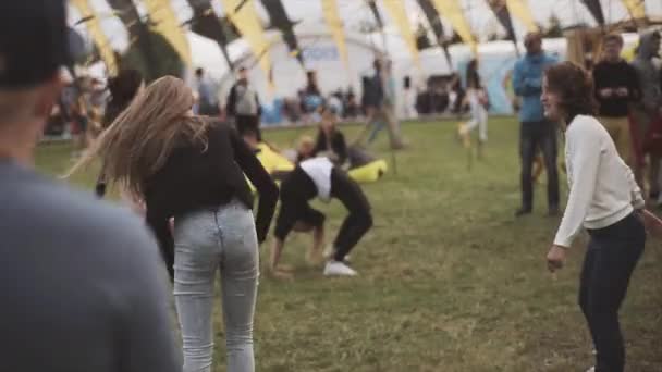 SAINT PETERSBURG, RÚSSIA - 16 de julho de 2015: Jovens meninas fazem acrobacias na grama no festival de verão. Público. Entretenimento. Bandeiras ondulantes — Vídeo de Stock