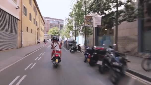 BARCELONA, ESPAÑA - 7 DE JUNIO DE 2015: Parte trasera de la gente en cascos monta en scooters en la ciudad. Gente. Arquitectura. Motos estacionadas — Vídeo de stock