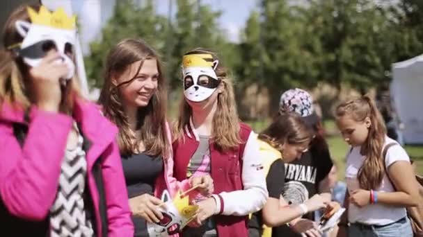 Saint Petersburg, Oroszország - 2015. július 16.: Tini lányok vicces arc maszkok tartson a nyári fesztivál. Süt a nap. Szórakozás — Stock videók