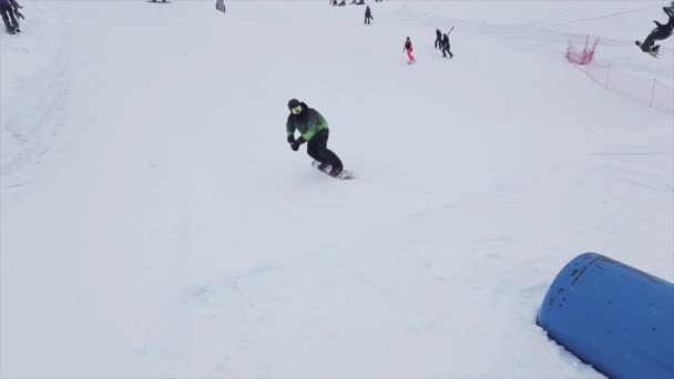 SOCHI, RUSIA - 29 DE MARZO DE 2016: Snowboarder retrocede en el trampolín en la pendiente. Estación de esquí en las montañas. Desafío. Jinetes . — Vídeos de Stock