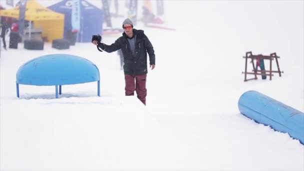 SOCHI, RÚSSIA - 29 de março de 2016: Cameraman shoot snowboarder jump on kicker at ski resort in mountains. Desporto extremo. Pessoas — Vídeo de Stock