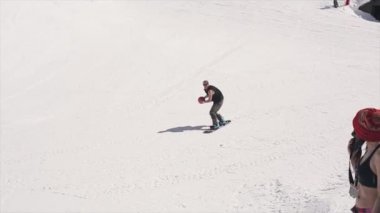 Soçi, Rusya - 1 Nisan 2016: Yamaç üzerinde Snowboarder binmek basketbol sepeti içine topu atmak. Peyzaj dağları