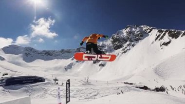 Soçi, Rusya - 1 Nisan 2016: Sıçrama tahtasından atlayan iki snowboardcu havada tam takla atıyor. Karlı dağların manzarası. Mavi gökyüzü