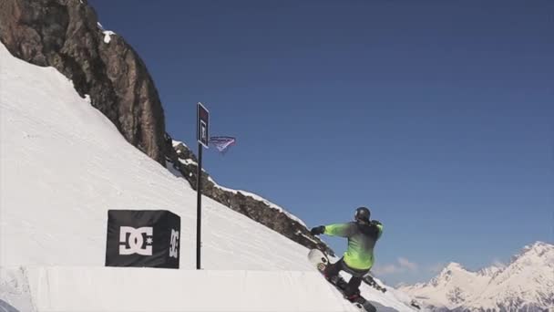 SOCHI, RUSIA - 1 DE ABRIL DE 2016: Paseo snowboarder en el trampolín hacer voltear la canasta de baloncesto. Soleado. Gente — Vídeos de Stock