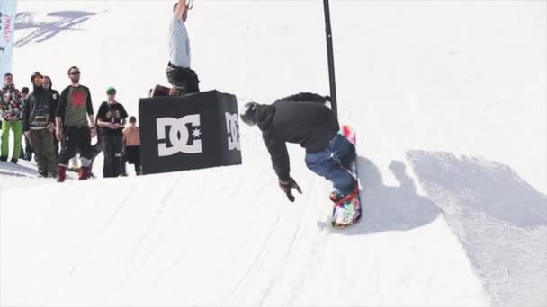 SOCHI, RUSIA - 1 DE ABRIL DE 2016: Paseo snowboarder en trampolín lanzar bola de nieve en la canasta de baloncesto. Hacer voltear — Vídeos de Stock