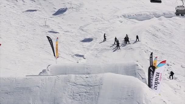SOCHI, RUSSIA - 1 APRILE 2016: Snowboarder salto in alto dal trampolino di lancio. Montagne di neve. Giornata di sole. Gente. Sport estremi. Località sciistica — Video Stock