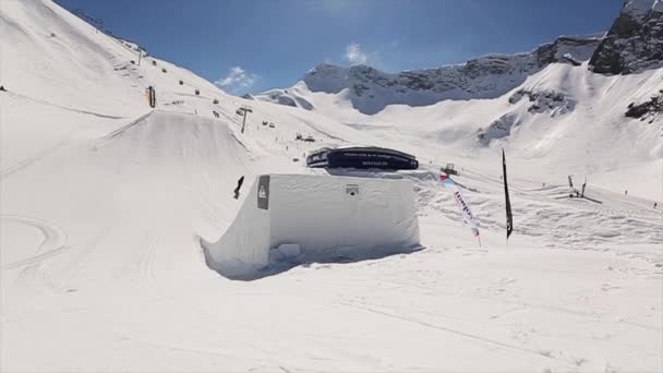 SOCHI, RUSIA - 1 DE ABRIL DE 2016: Paseo en snowboarder en pendiente. Paisaje de montañas nevadas. Cielo azul. Día soleado. Estación de esquí. Gente — Vídeo de stock