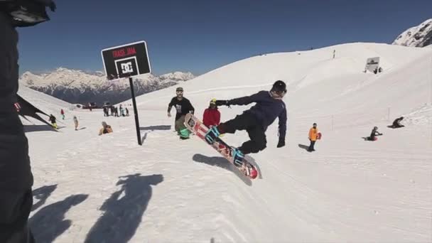 Sotschi, Russland - 1. April 2016: Snowboarder springen auf Sprungbrett und machen Salto in der Luft. Basketball-Korb. Sonne — Stockvideo